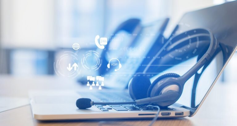 close up headset of call center and laptop with virtual futuristic communication telephony voip technology on office desk in monitoring room for network operation job concept